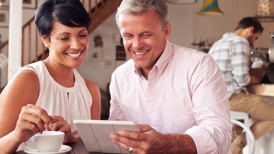 Mature couple in coffee shop, looking at tablet